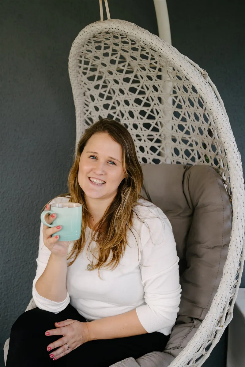 Brittany with a mug of tea in a hanging wicker chair.