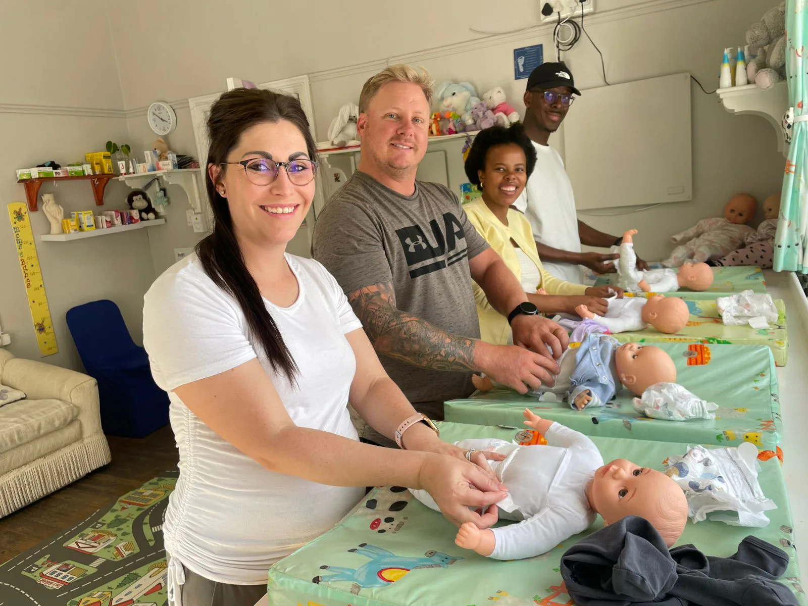 Parents practising nappy changing and dressing on baby dolls