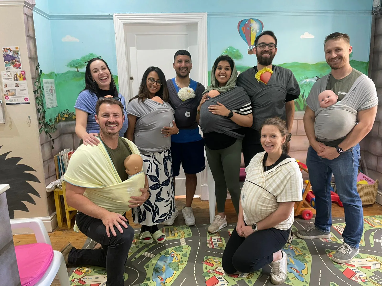 Parents at an antenatal class practising baby-wearing with wraps and dolls