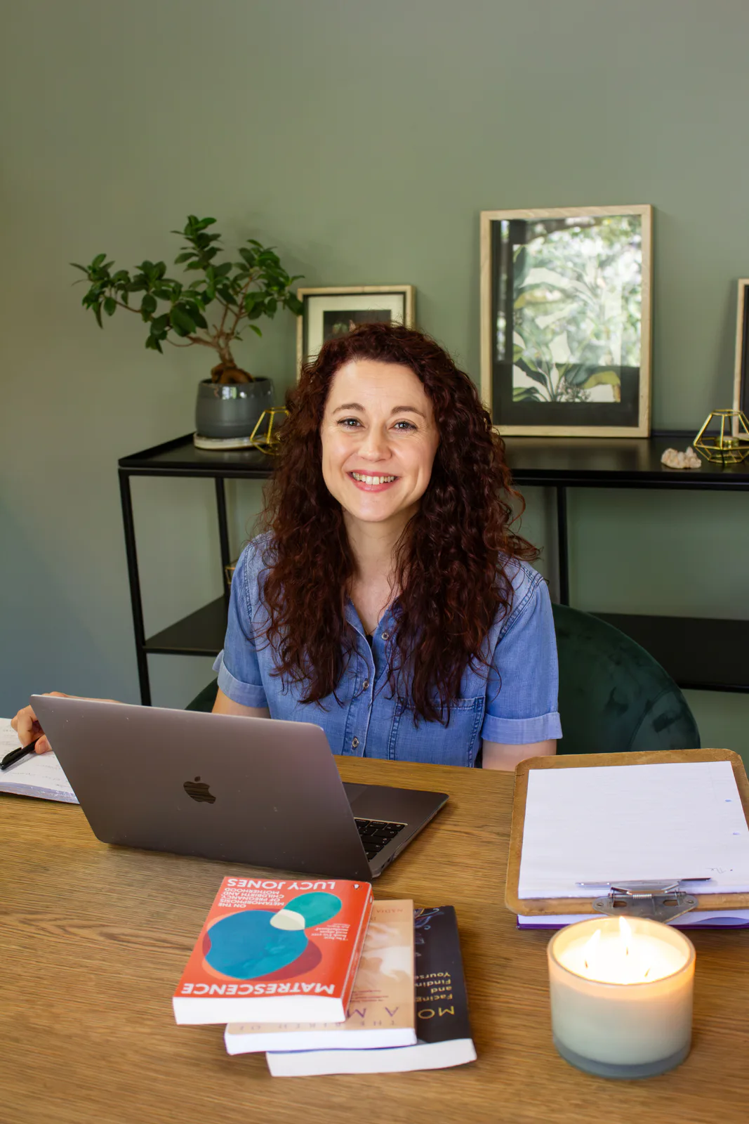 Dr Kim Wale at her desk with her laptop and books on matrescence