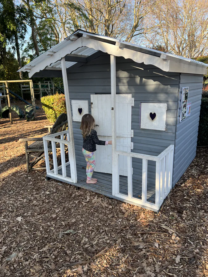 A child playing in the wooden playhouse at Ferndale Nurseries