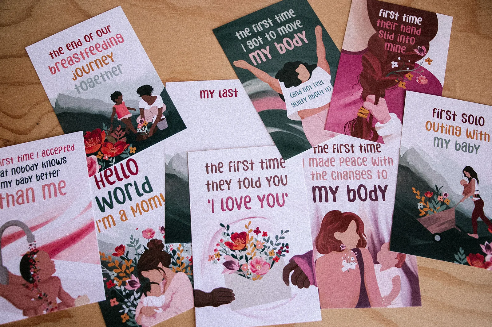 A spread of milestone cards for moms laid out on a wooden table