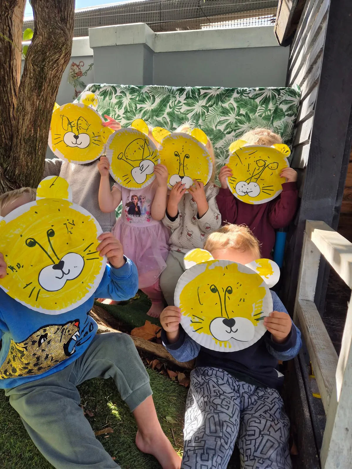 Children holding up paper-plate lion masks they have painted
