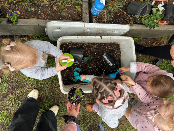 Children potting seedlings around a soil tray at a Mamma’s Plants workshop