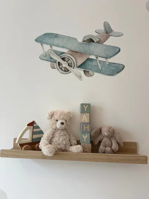 Blocks spelling Yahya stacked on a nursery shelf beside a teddy and a bunny