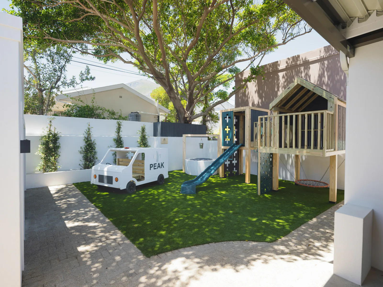 The practice playground, with a slide, jungle gym, swing and a wooden play ambulance
